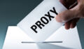 Voter's hand holding a proxy vote ballot, inserting the vote card into the ballot box.