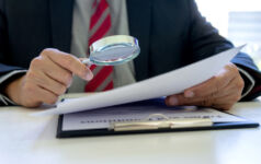 Lawyer or judge use magnifier glass look to the paper for inspection examination to the law case