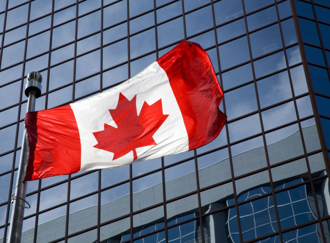 Canadian flag in front of modern building.