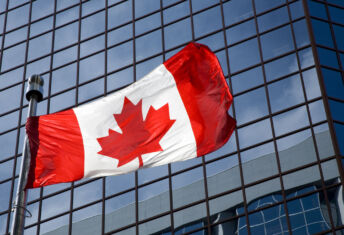 Canadian flag in front of modern building.