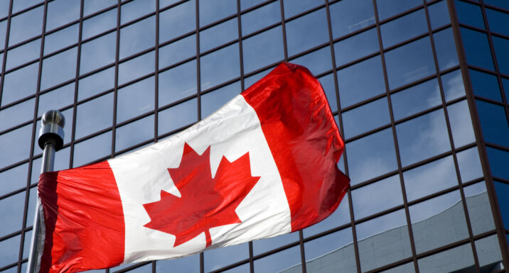 La Caisse passes halfway mark on 2030 climate action investment target Canadian flag in front of modern building.