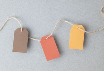 Autumn color palette, blank gift tags with jute twine string on a gray textured surface with copy space.