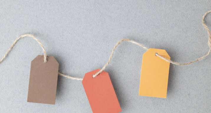 Autumn color palette, blank gift tags with jute twine string on a gray textured surface with copy space.