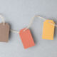 European Commission leaning towards tabling three SFDR product categories Autumn color palette, blank gift tags with jute twine string on a gray textured surface with copy space.