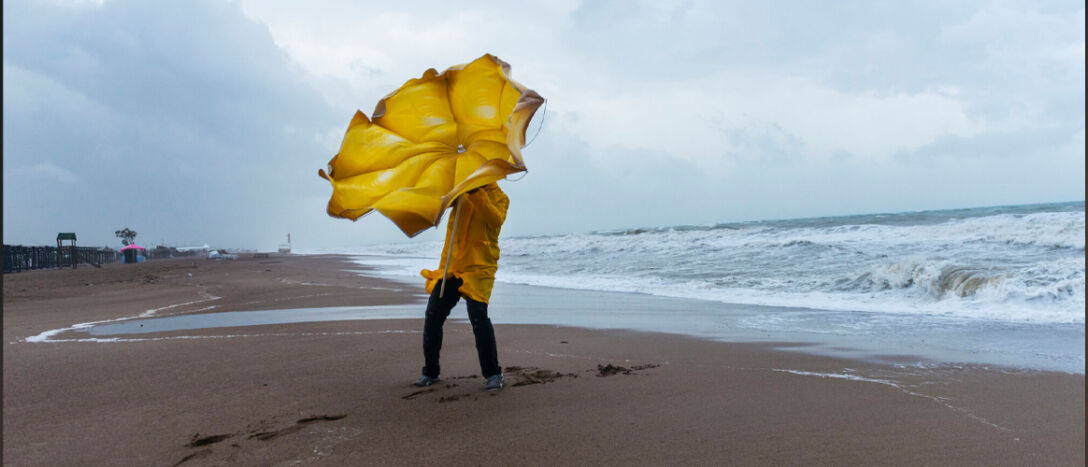 T9-wind umbrella Person on a beach trying to hold an umbrella on a windy day