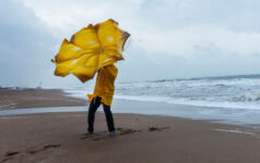 Person on a beach trying to hold an umbrella on a windy day