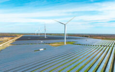 Photo of a windmill in a field with windmills in the back.
