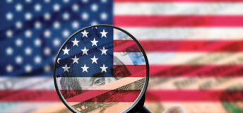 A magnifying glass focusing on American bills and flag