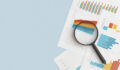 Business graphs, charts and magnifying glass on table