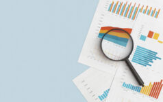 Business graphs, charts and magnifying glass on table