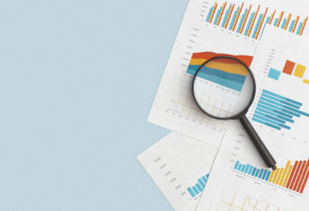 Business graphs, charts and magnifying glass on table