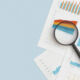 Business graphs, charts and magnifying glass on table