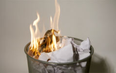 A photo of a waste paper basket that has been set on fire