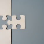 PRI initiative aims to align owners and managers on system-level risks Two puzzle pieces connecting, one white and one grey, on a contrasting background