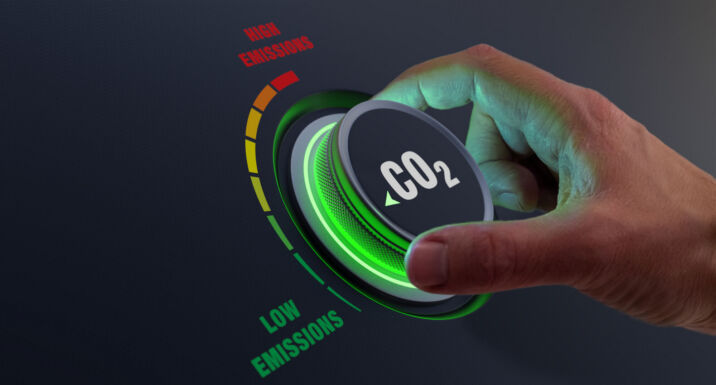 Big read: Can asset owners move the needle on UK transition plans? Hand turning dial marked CO2 to "low emissions"
