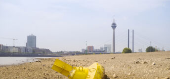 Low stream gauge of rhine river.Water shortage, drought, climate change,global warming concept, dry river bed with skyline of the town of düsseldorf, germany in the background