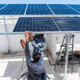 Can blended finance reach scale for emerging market climate action? Getty, Indian workers installing solar panels on roof of house.
